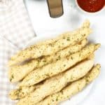 Cooked breadsticks next to air fyrer and cause on the side with a taupe checked napkin