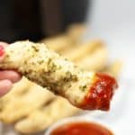 Hans holding a air fryer garlic breadstick dipped in sauce