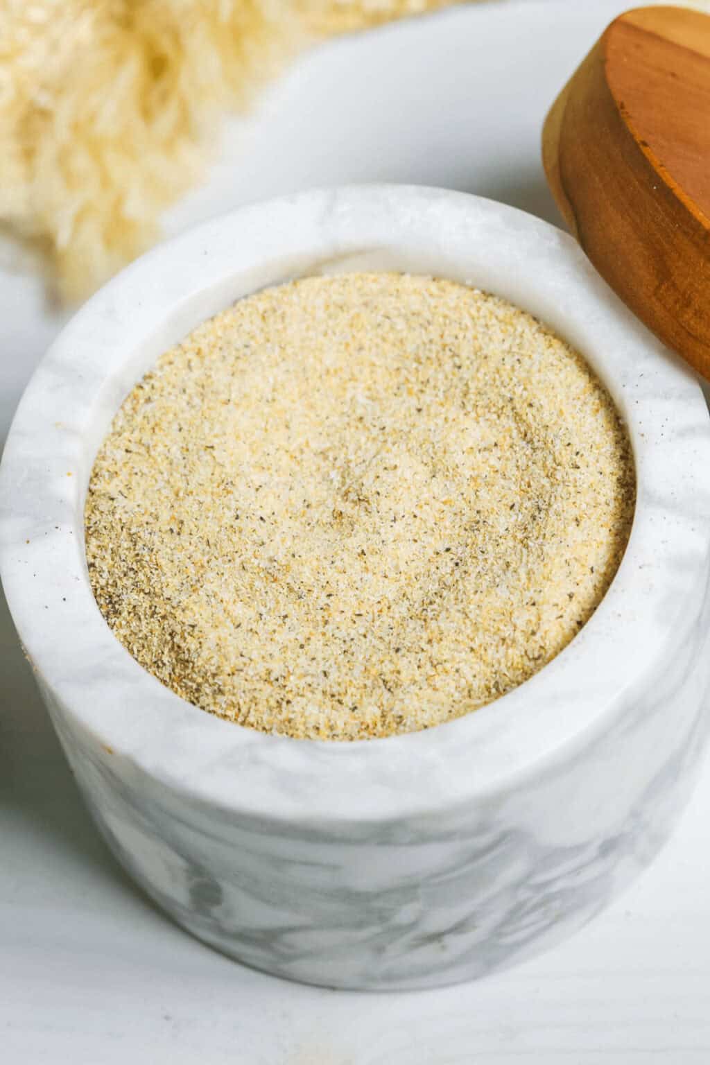 A marble container with all purpose seasoning inside.