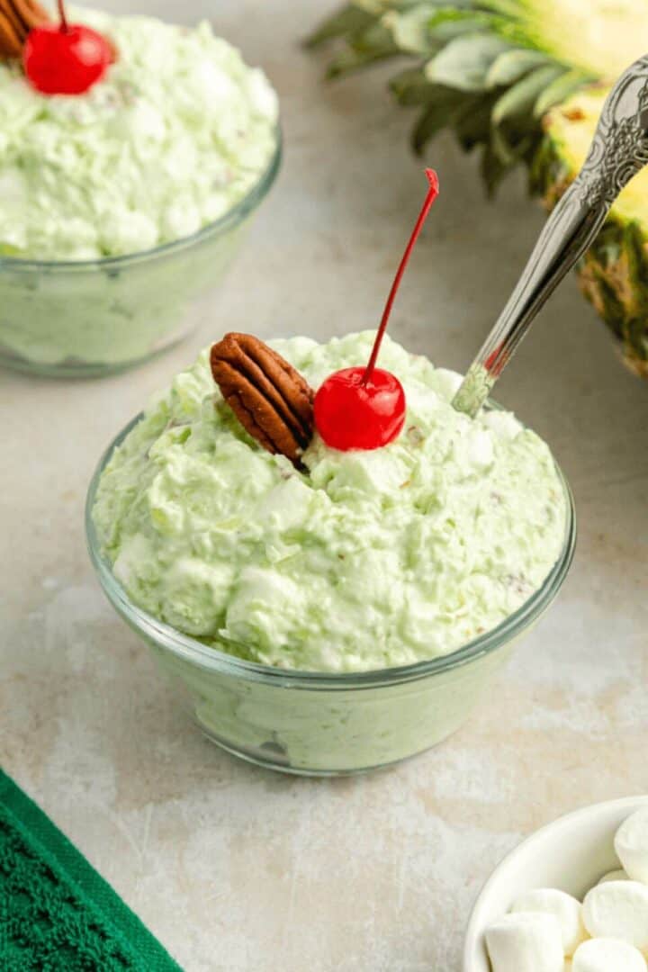 A serving of the ambrosia watergate salad with a cherry on top.