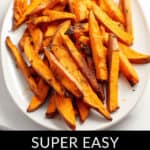 An oval white plate filled with crispy, delicious baked sweet potato fries. Text below the image reads, "Super Easy Baked Sweet Potato Fries.