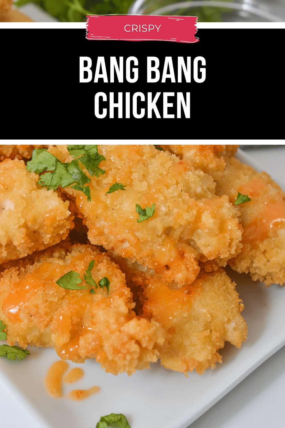 A plate of crispy Bang Bang Chicken pieces garnished with a drizzle of sauce and fresh herbs.