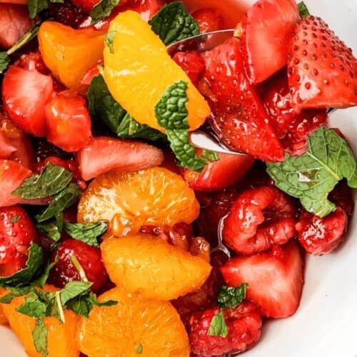 A white bowl of the breakfast fruit salad with honey lime dressing.