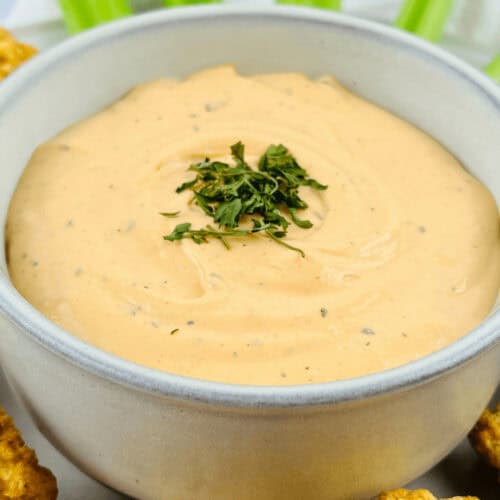 A bowl of buffalo ranch dip with celery and celery sticks.