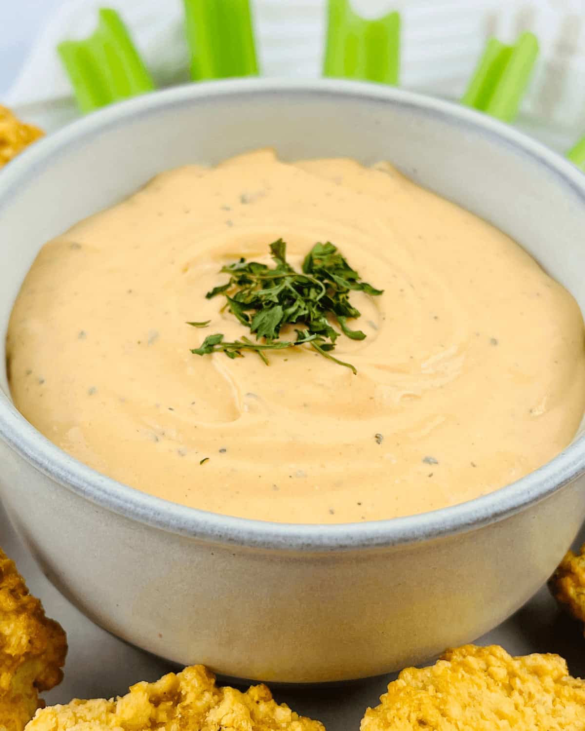 A bowl of buffalo ranch dip with celery and celery sticks.