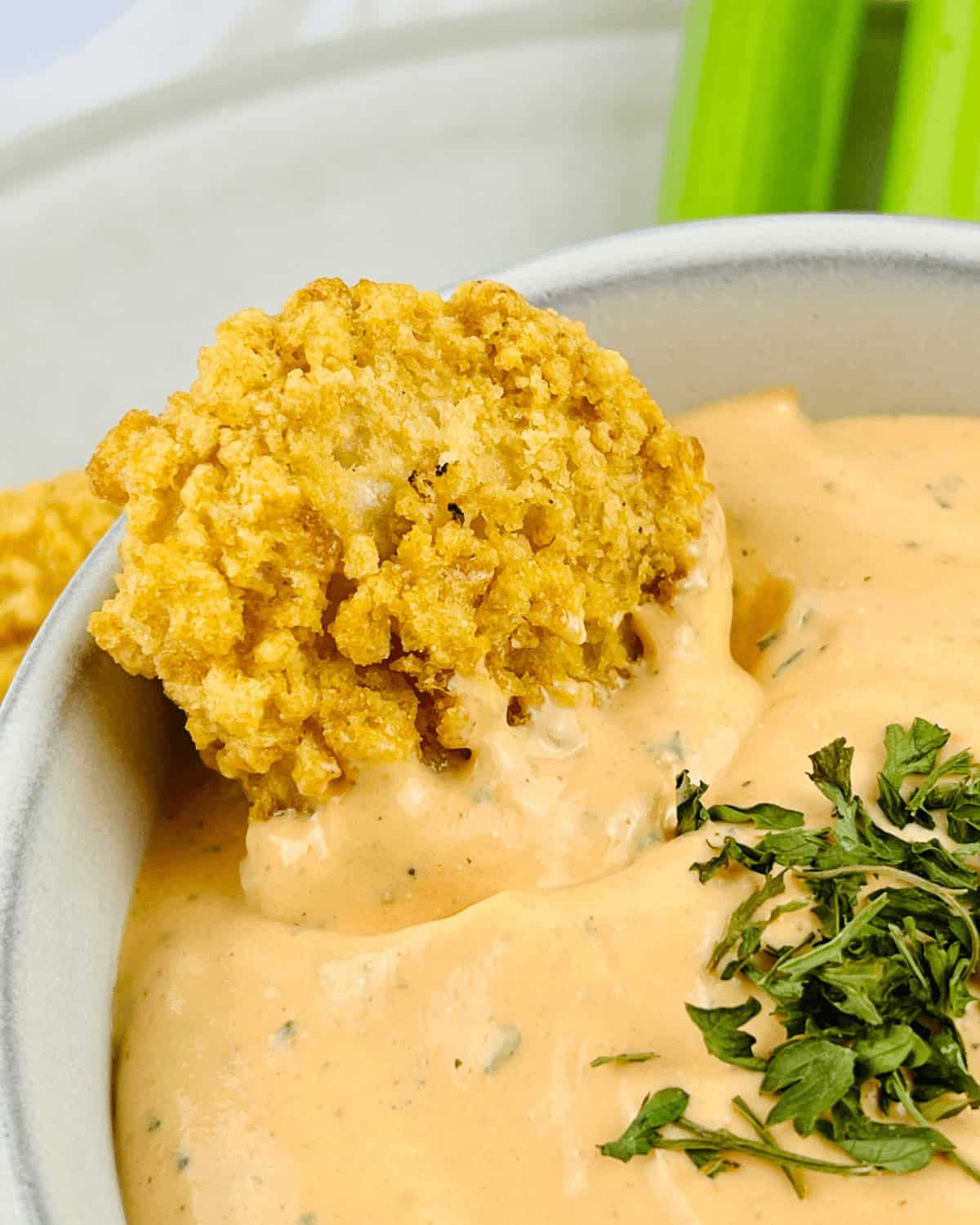 A white bowl with the sauce and celery sticks.