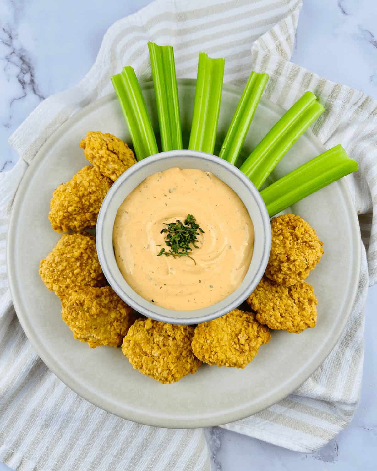 Chicken nuggets with ranch dip on a plate.