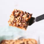 A piece of chocolate oat bars is being picked up.