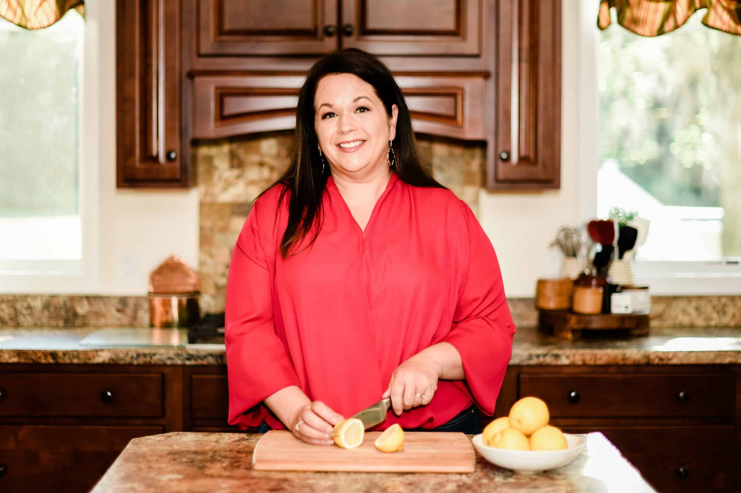 Woman in red blouse slicing lemons in a kitchen setting.