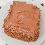 A rectangular piece of Cocoa Mayonnaise Cake with chocolate frosting sits on a white plate.