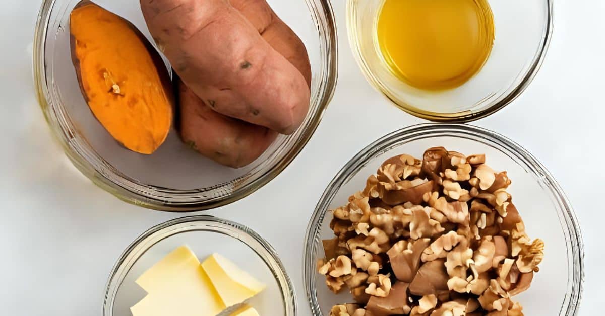 Four glass bowls containing Maple Sweet Potatoes, olive oil, shelled walnuts, and slices of butter are arranged on a white surface.
