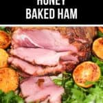 Copycat honey-baked ham slices rest on a plate, elegantly garnished with grilled orange halves and fresh greens.