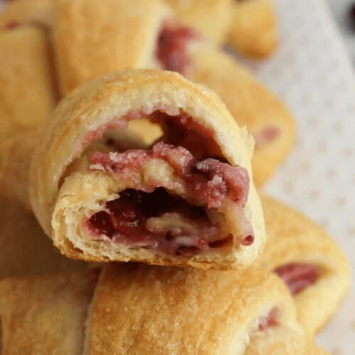 A cranberry cheesecake crescent roll with a bite taken out.