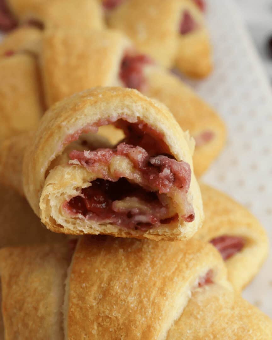 A cranberry cheesecake crescent roll with a bite taken out.