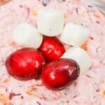 A close-up of creamy fruit dessert, topped with three mini marshmallows—a festive holiday dessert.