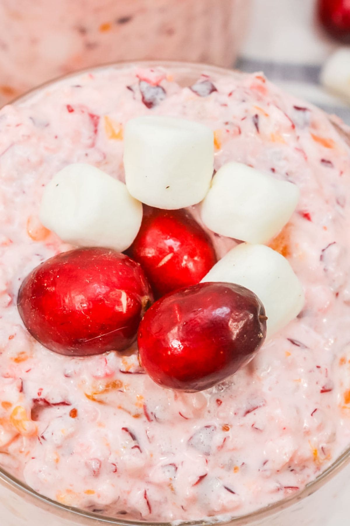 A close-up of creamy fruit dessert, topped with three mini marshmallows—a festive holiday dessert.
