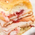 A close-up featuring sliced meat and tangy sauce on a soft, seeded bun.