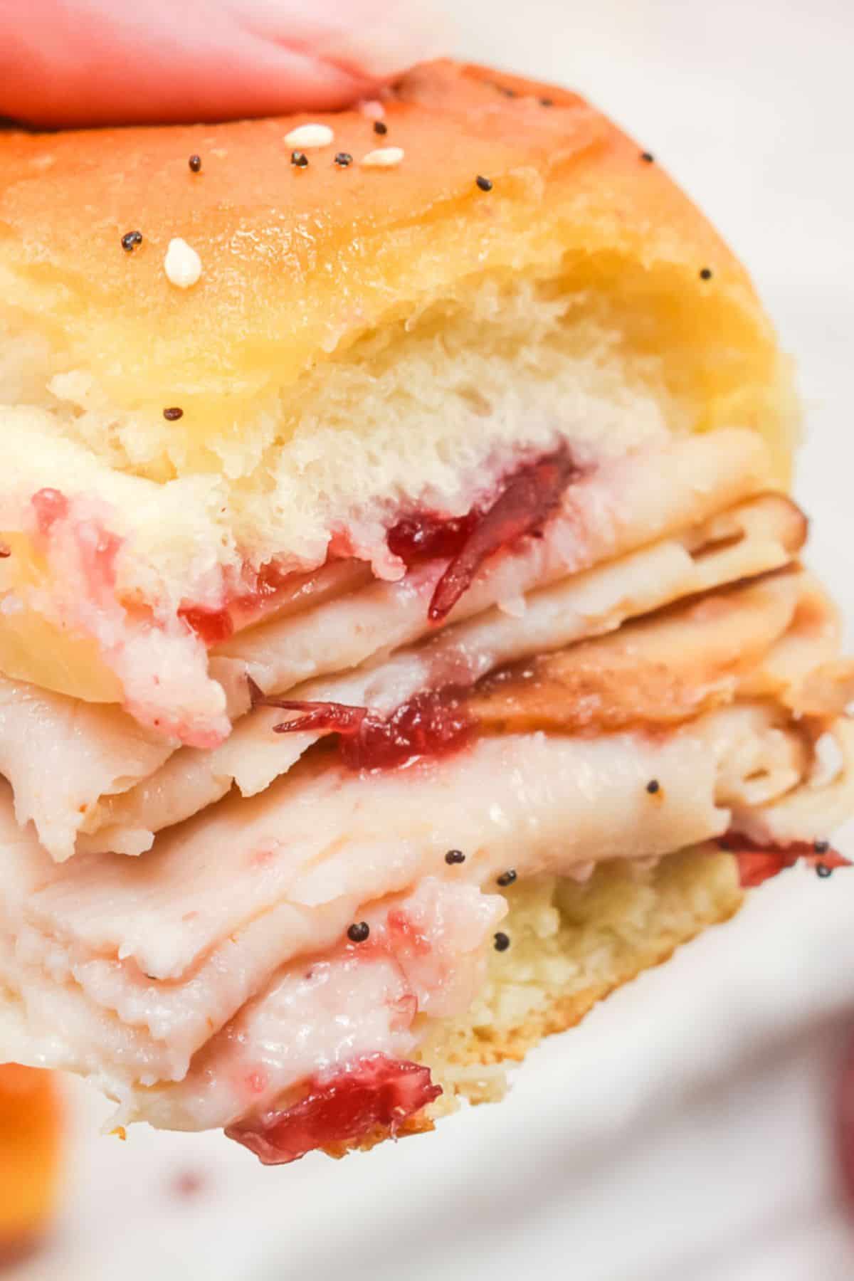 A close-up  featuring sliced meat and tangy  sauce on a soft, seeded bun.