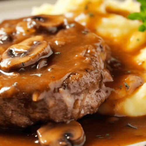 A plate of crock pot salisbury steak with mashed potaotes.