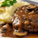 Meat with gravy on a white plate.