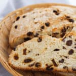 Easy Irish Soda Bread sliced with raisins, elegantly arranged on a wicker plate, rests on a gray napkin.