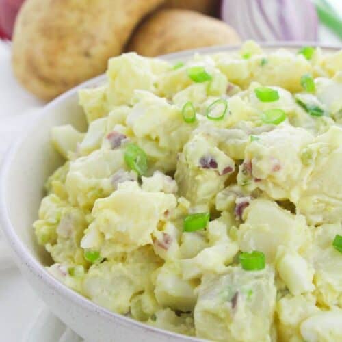 A white bowl of the dish with the vegetables in the background.