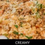 A plate of creamy Sausage Risotto, garnished with grated cheese and fresh herbs, with text overlay reading "Creamy Easy Sausage Risotto.