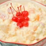 Cherries on top of a fruit salad with cool whip.