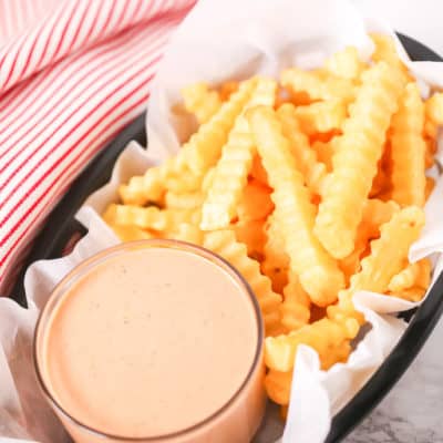 Basket of fries with red and white stripped napkin with fry sauce