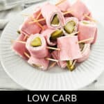 Plate of delicious pickle roll-ups on toothpicks, aptly labeled "Low Carb Ham and Pickle Roll Ups," resting on a striped cloth background.