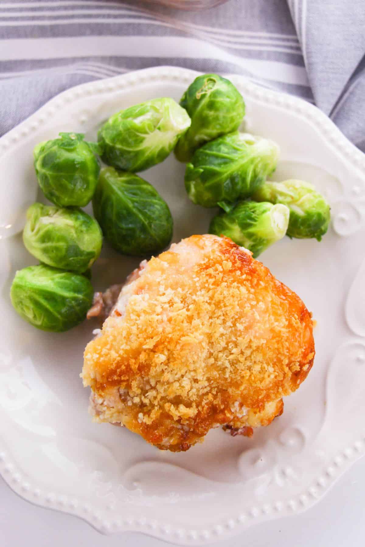 A plate with Hellman's Crusted Parmesan Chicken thigh, baked to perfection, and a serving of steamed Brussels sprouts.