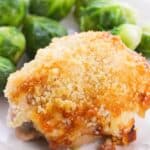 A serving of Hellman's Crusted Parmesan Chicken, baked to perfection with a golden breadcrumb crust, plated alongside steamed Brussels sprouts.