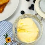 Glass mason jar holding homemade butter with blue and white flower napkin with flower.