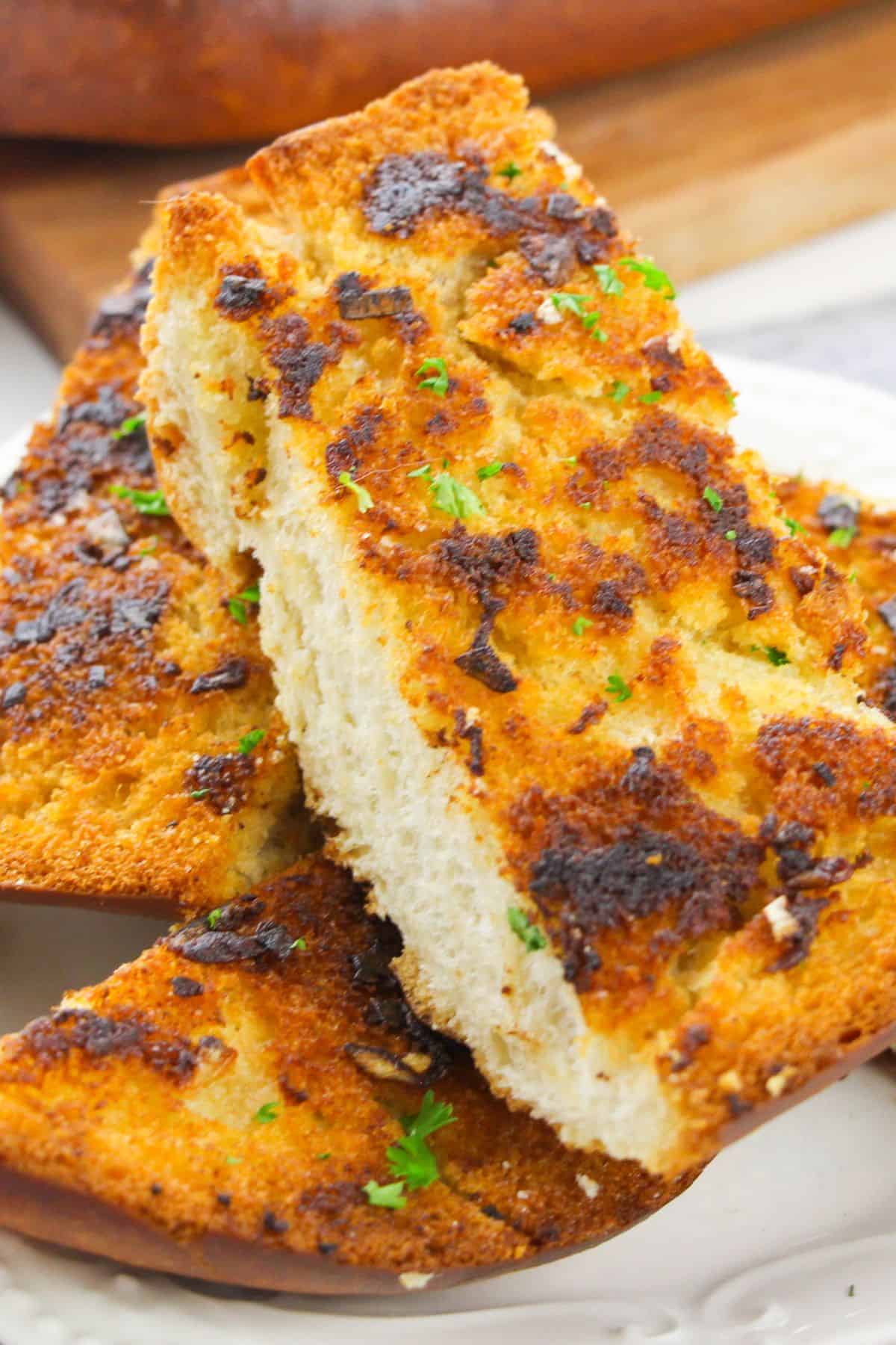 Two slices with a crispy, golden-brown top and sprinkled with chopped herbs, served on a white plate.