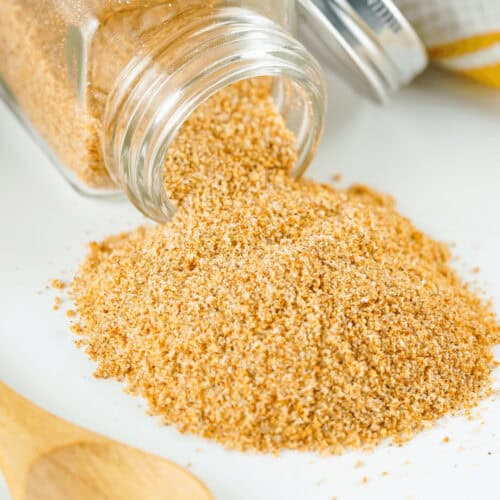 A jar of homemade seasoned salt sits next to a wooden spoon.