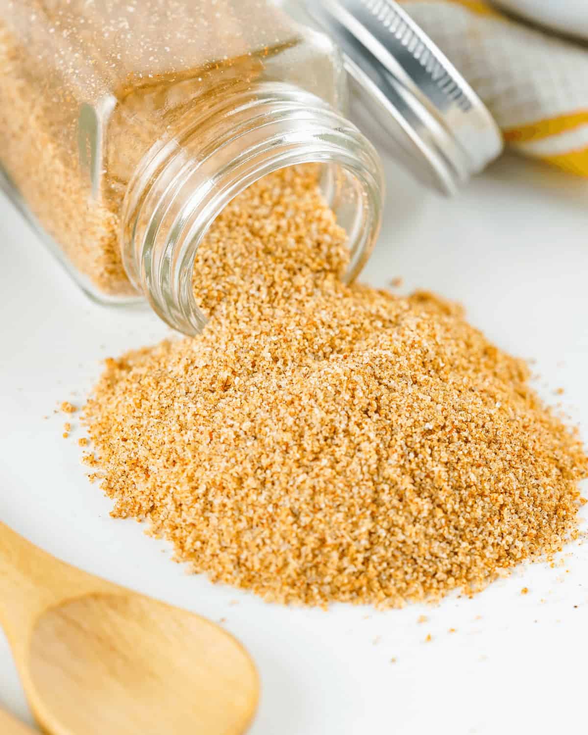 A jar of homemade seasoned salt sits next to a wooden spoon.