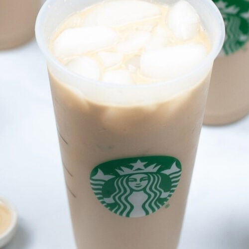 A plastic cup filled with Iced White Chocolate Mocha from Starbucks, featuring the iconic green siren logo on the front.