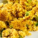 Plate of Jiffy Cornbread Dressing with visible pieces of celery and onions, served on a white dish.