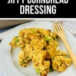 A plate with a serving of Jiffy Cornbread Dressing, garnished with green vegetables, sits beside a wooden fork on a white plate, with a baking dish of Jiffy Cornbread Dressing in the background.