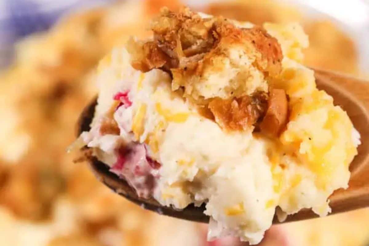 A close-up of a spoonful of leftovers casserole with mashed potatoes, stuffing, turkey, and gravy.