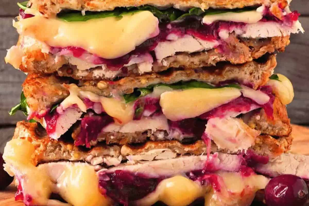 Close-up of a crispy panini stuffed with turkey, cheese, and cranberry sauce.