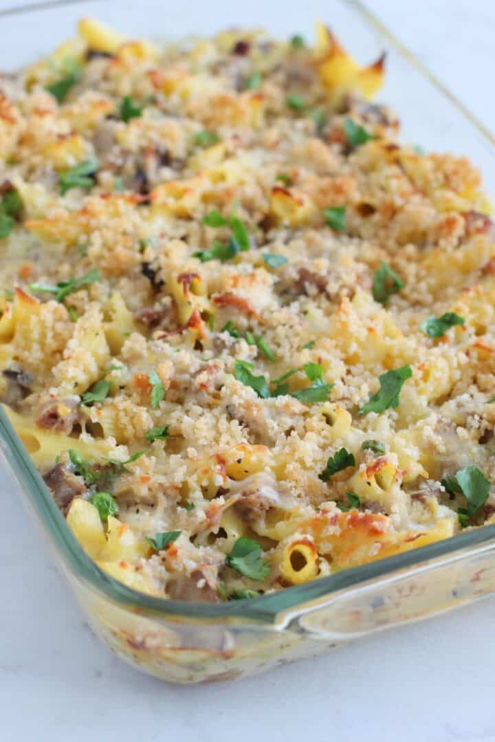 A glass baking dish filled with a savory Turkey Pasta Recipe casserole, topped with golden breadcrumbs and garnished with chopped parsley.