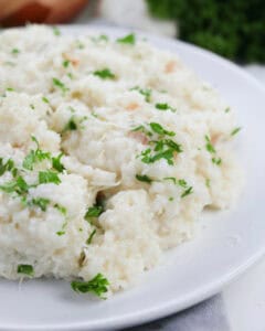 Creamy lemony shrimp risotto served on a white plate, garnished with parsley.