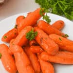 A plate of maple-glazed baby carrots, perfectly garnished with fresh parsley.