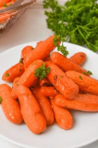 A plate of maple-glazed baby carrots, perfectly garnished with fresh parsley.
