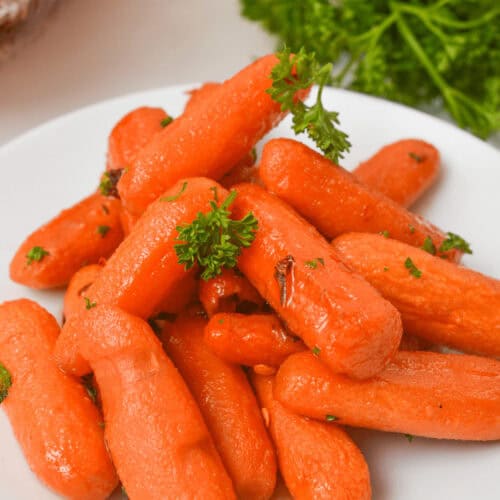 A plate of maple-glazed baby carrots, perfectly garnished with fresh parsley.