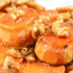Maple Sweet Potatoes: Sliced glazed sweet potatoes topped with chopped walnuts on a white plate.