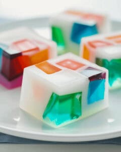 A mosaic of colorful jelly cubes on a white plate.