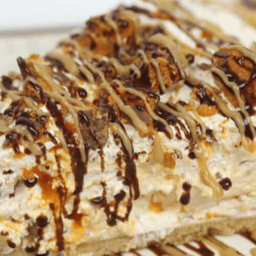 A decadent Butterfinger Pie slice topped with chocolate drizzle and cookie pieces on a decorative plate.