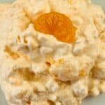 A mandarin orange slice on top of orange fluff.